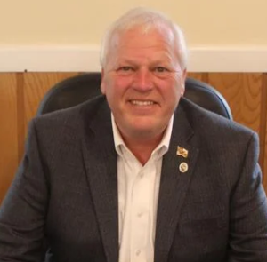 Portrait of a smiling mature man in a suit, showcasing a professional demeanor. The image captures a confident and approachable figure.